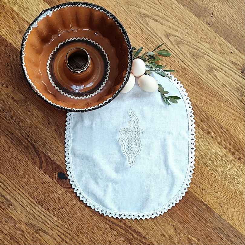 Ročno izdelan velikonočni prtiček z nežno klekljano čipko. Ovalna oblika in klekljan motiv križa s plameni. Možna izdelava v velikosti po naročilu.