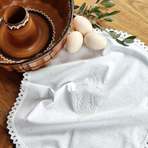 Ročno izdelan velikonočni prtiček z nežno klekljano čipko. Ovalna oblika in klekljan motiv križa s plameni. Možna izdelava v velikosti po naročilu.